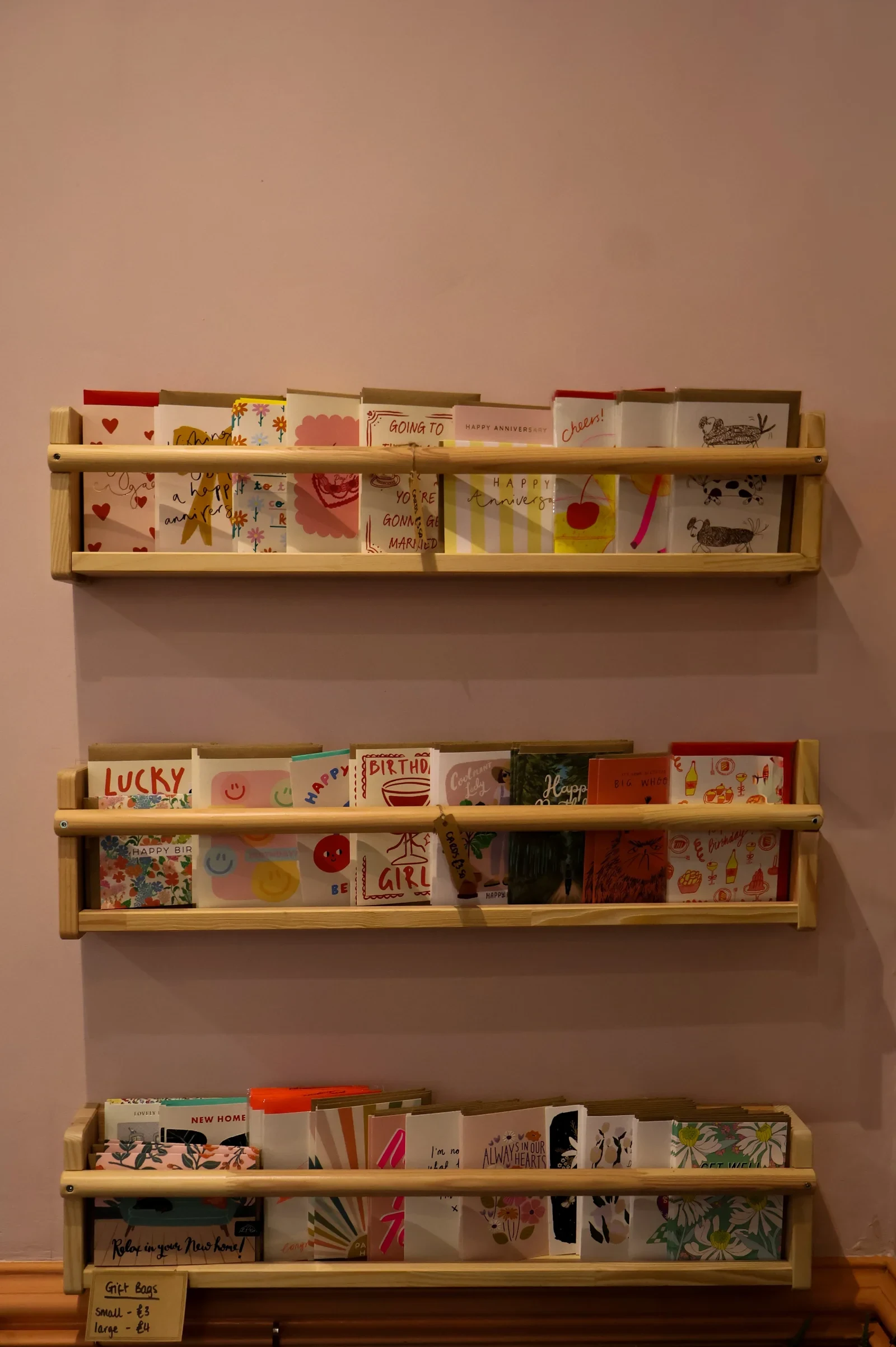 Greeting cards arranged on pink shelves at Roots